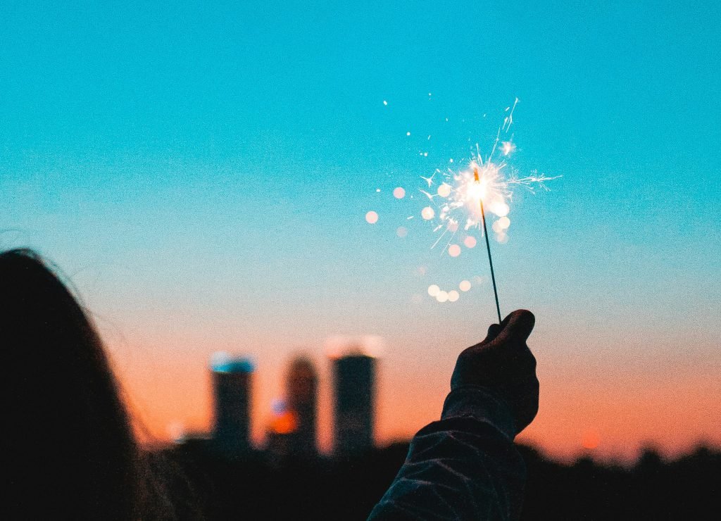 Sparkler held by silouette during blue and orange sunset