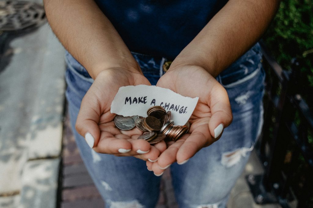 person holding coins in their hand with a piece of paper that says "make a change" on it