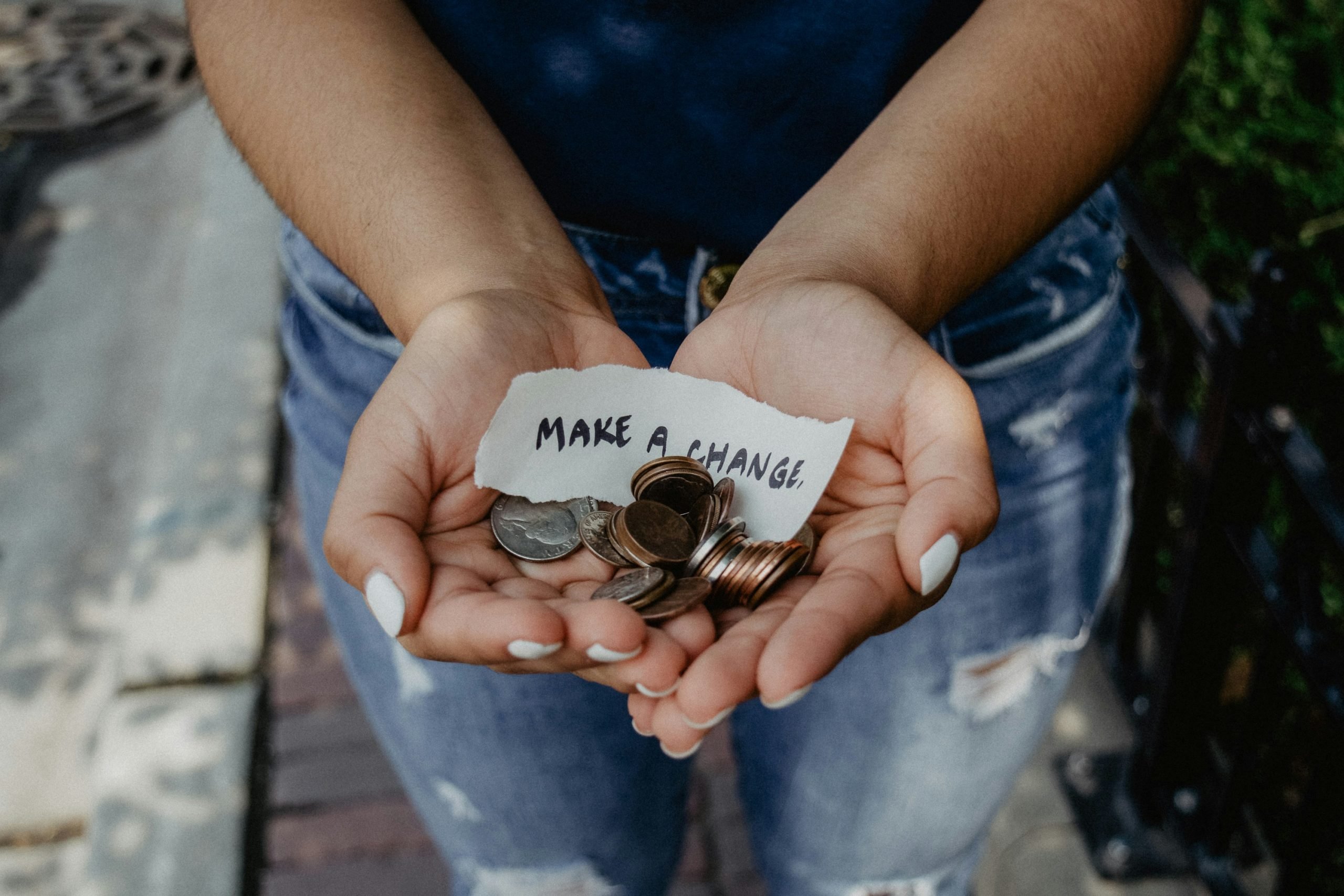 person holding coins in their hand with a piece of paper that says "make a change" on it
